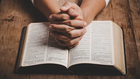 Praying hands over a bible